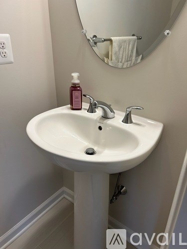 A white sink with a pink soap dispenser and a silver faucet.