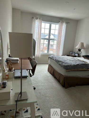 A bedroom with a bed, desk, and window.