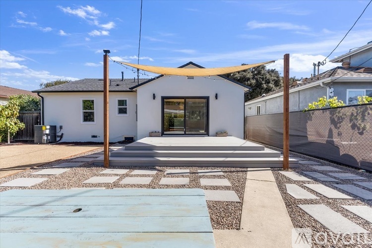 A white house with a yellow awning and a stone walkway leading to the front door.