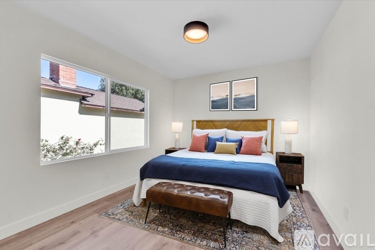 A bedroom with a bed, bench, and two lamps.