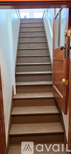 A set of stairs leading up to a door with a brass handle.