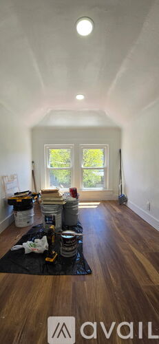 A room with wooden floors and a window with a view of trees.
