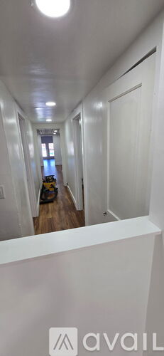 A long white hallway with a light on the ceiling.