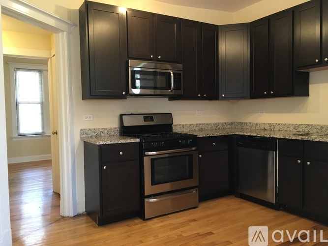 A kitchen with black cabinets and a granite countertop.