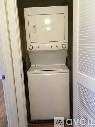 A white dishwasher is in a small space next to a window.