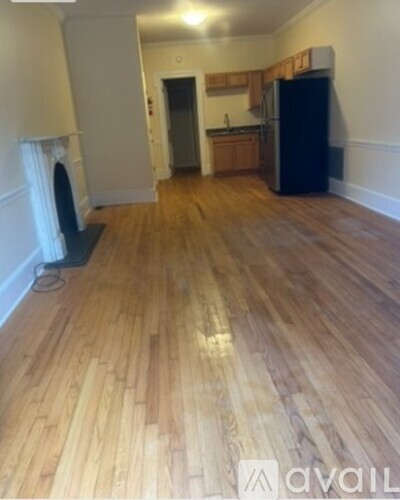 A room with wooden flooring and a black fridge.