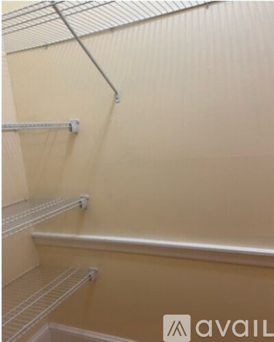 Empty pantry with white shelves and beige walls.