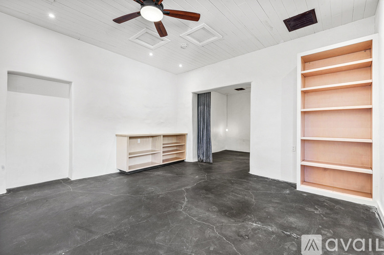 A spacious room with a ceiling fan and a built-in shelf.
