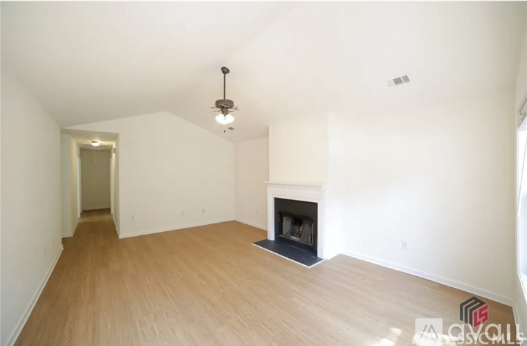 A large, empty room with a fireplace and wooden flooring.