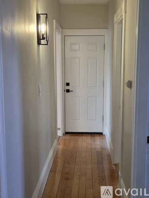 A hallway with a white door and a light on the wall.