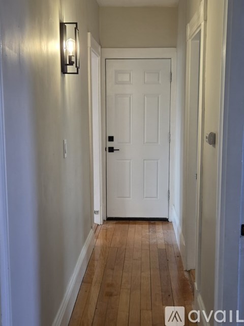 A hallway with a white door and a light on the wall.
