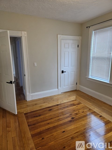 A room with a white door and a wooden floor.