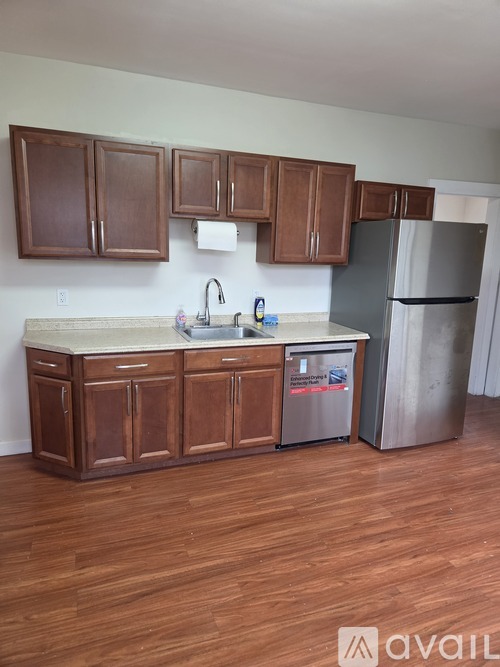 A kitchen with wooden cabinets and a stainless steel refrigerator.