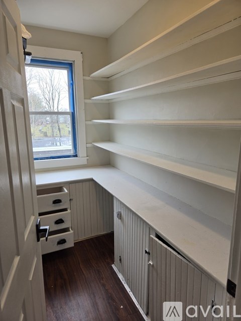 A kitchen with white shelves and a window.