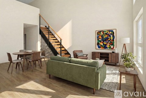 A living room with a green couch, a wooden staircase, and a painting on the wall.