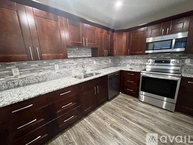 A kitchen with dark wood cabinets and a granite countertop.