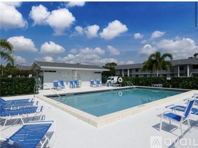 A pool with blue chairs and a building in the background.