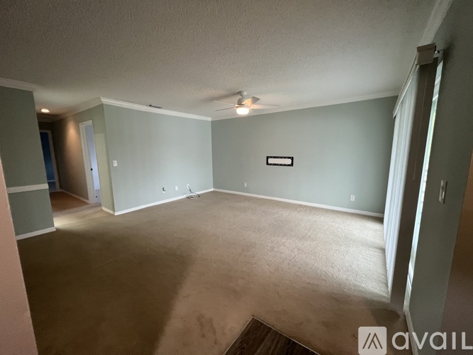 A spacious room with a carpeted floor and a ceiling fan.