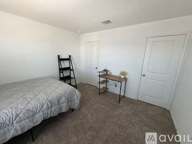 A bedroom with a bed, desk, and chair.