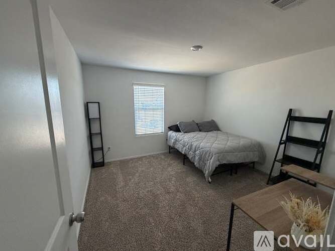 A bedroom with a bed, a chair, and a window with blinds.