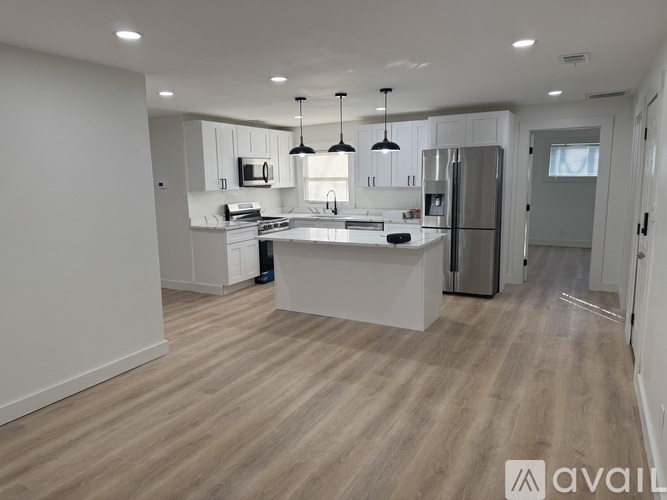 A modern kitchen with wooden flooring and white cabinetry.