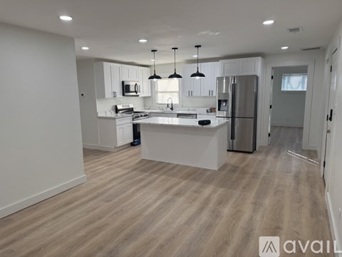 A modern kitchen with wooden flooring and white cabinetry.