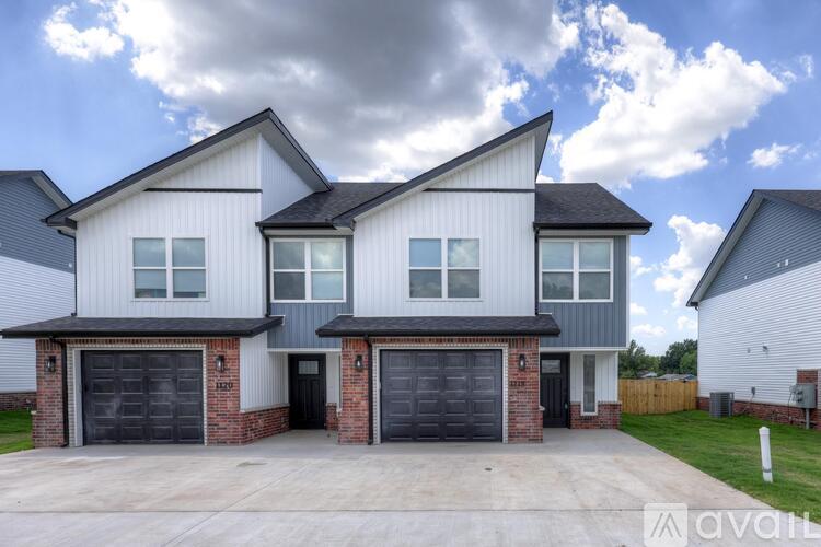 A modern house with a grey and white exterior and a black garage door.