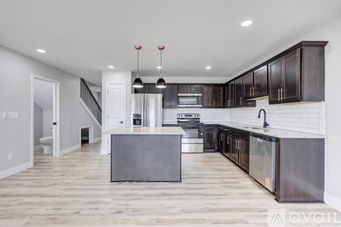 A modern kitchen with dark wood cabinets and stainless steel appliances.