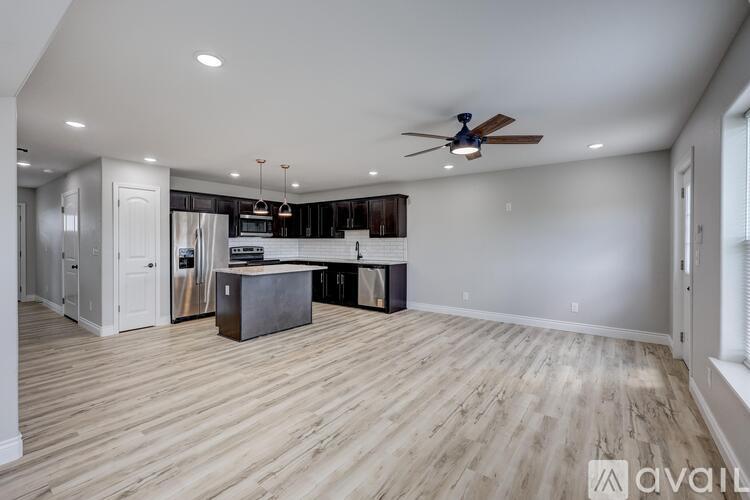 A spacious kitchen with a ceiling fan and wooden flooring.