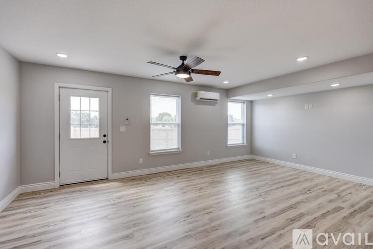 A spacious room with a ceiling fan and lighting, and a door leading to another room.
