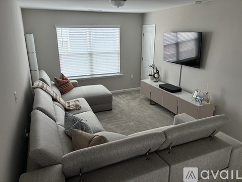 A living room with a grey sofa and a television on the wall.