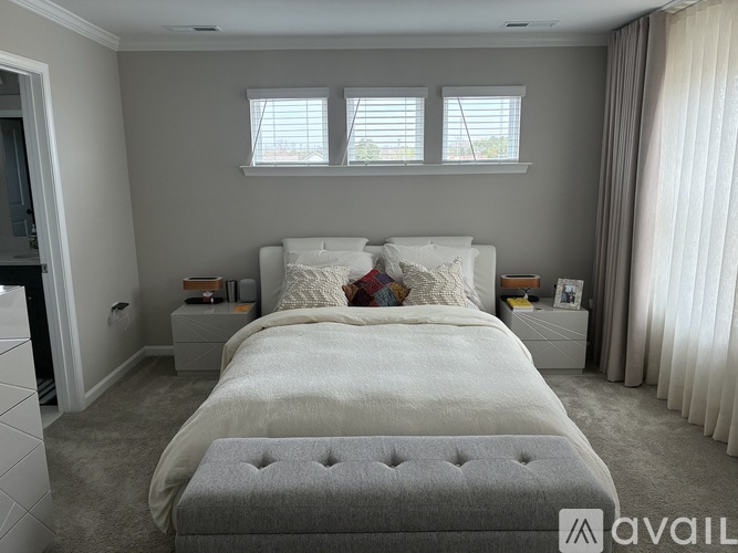 A bedroom with a large bed and a grey ottoman.
