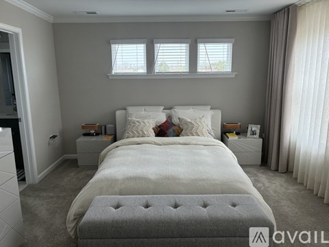 A bedroom with a large bed and a grey ottoman.