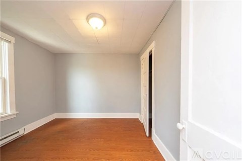 A room with wooden flooring and white walls.