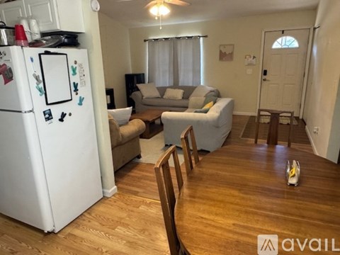 A kitchen with a white fridge and wooden floors.
