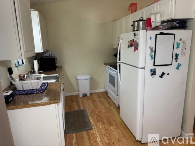 A kitchen with a white fridge and a white trash can.