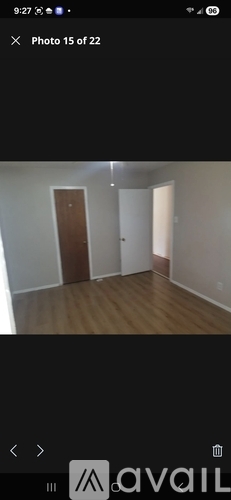 A room with wooden flooring and two doors, one of which is closed.