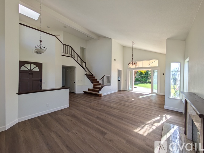 A spacious living room with hardwood floors and a staircase leading to the upper level.