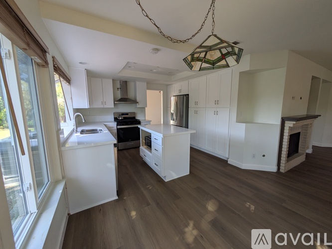A kitchen with white cabinets and a wooden floor.