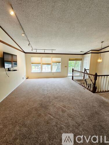 A spacious room with a carpeted floor and a television mounted on the wall.
