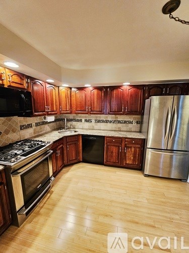 A kitchen with wooden cabinets and a stainless steel refrigerator.