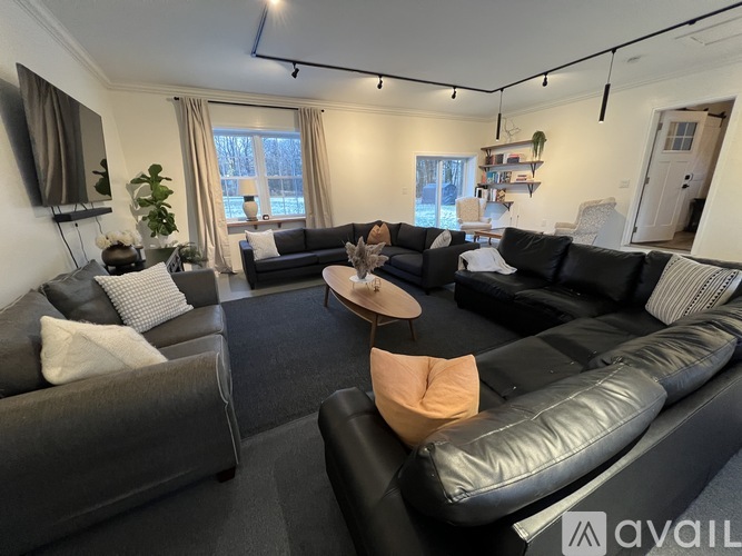 A living room with black leather couches and a wooden coffee table.