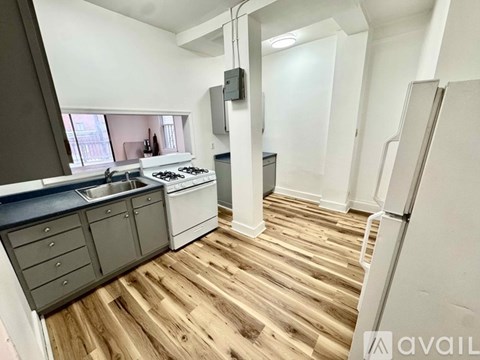 A kitchen with wooden floors and a white refrigerator.