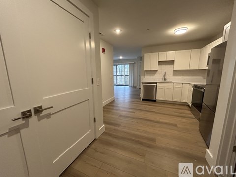 A kitchen with white cabinets and a wooden floor.