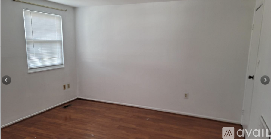 A room with wooden flooring and a window with blinds.
