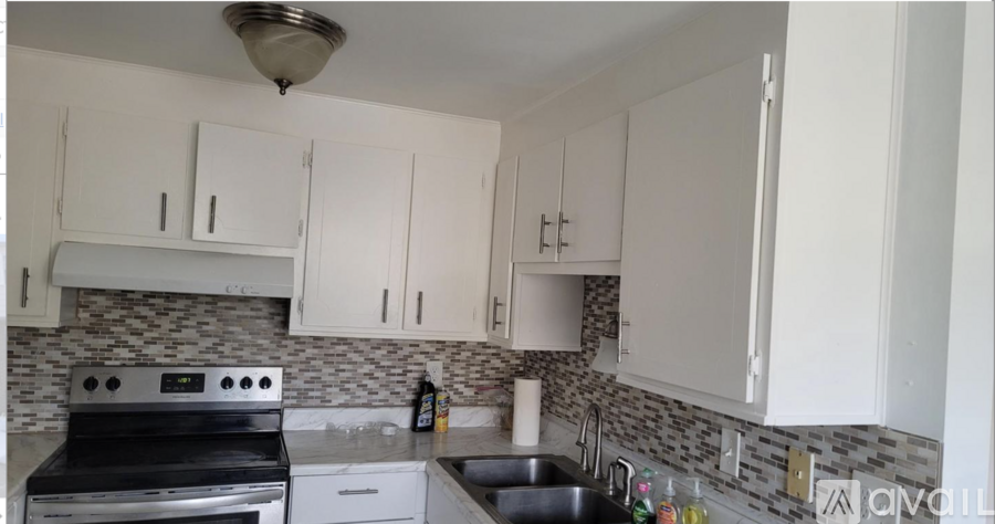 A kitchen with white cabinets and a black stove top oven.
