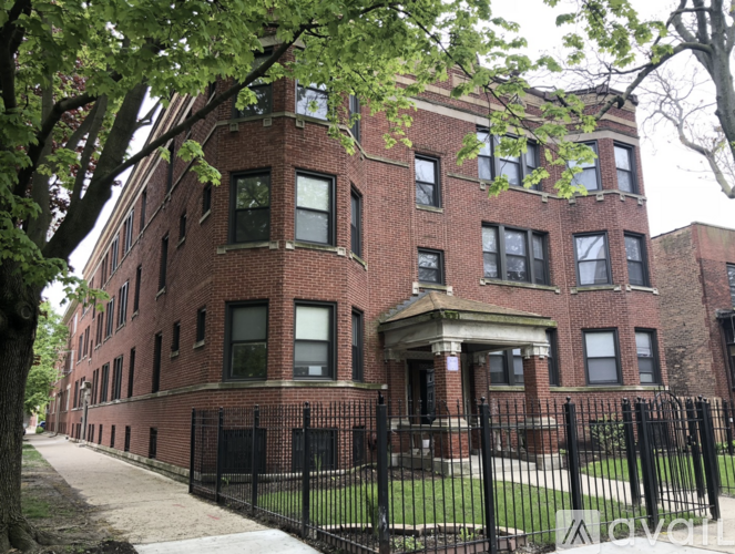 A red brick building with a black fence in front.