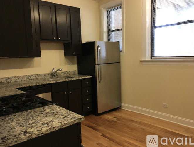 A kitchen with black cabinets and a granite countertop.