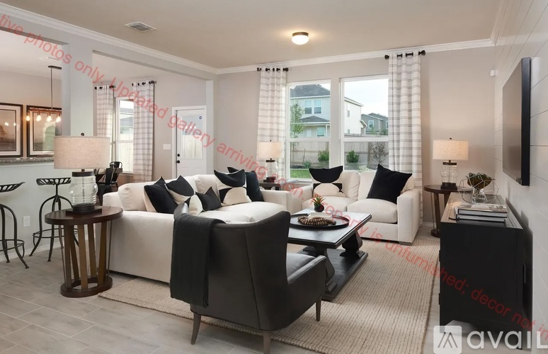 A modern living room with a white sofa, a black armchair, and a wooden coffee table.