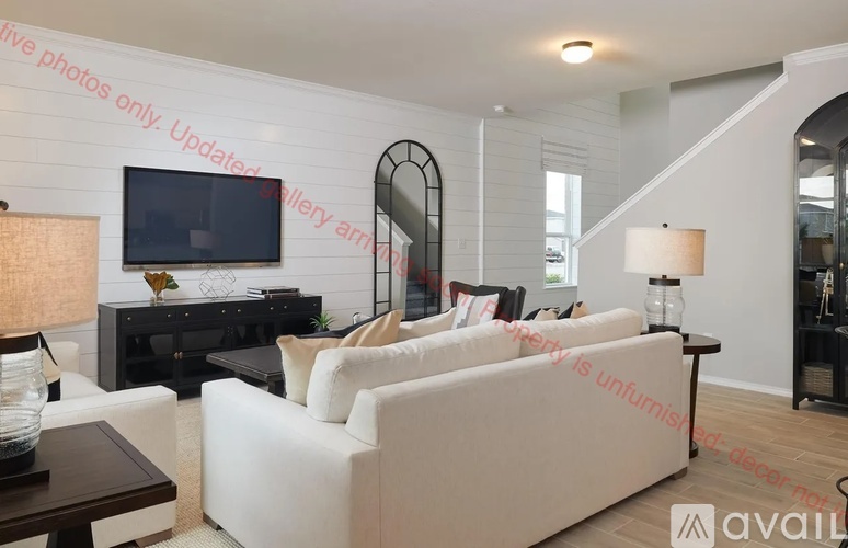 A living room with a white couch and a black entertainment center.